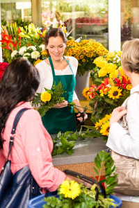 Young woman florist cutting flower shop customers